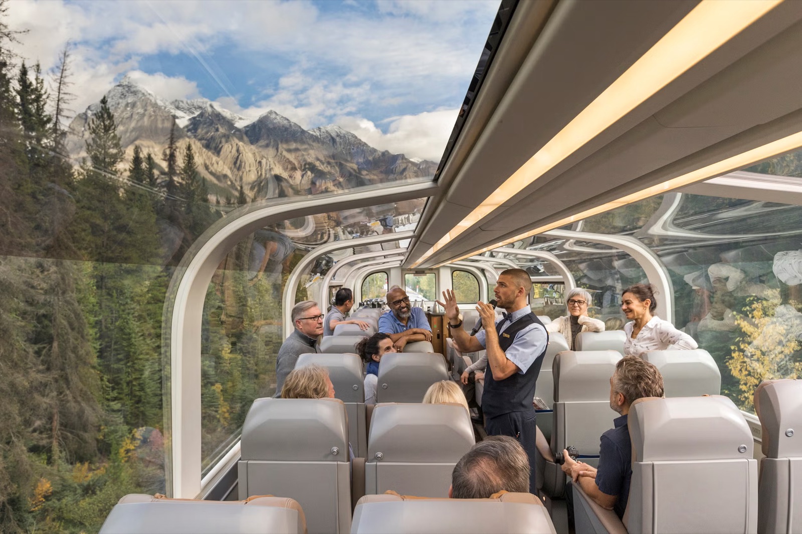 Guests in a Rocky Mountaineer glass-dome coach with mountain views