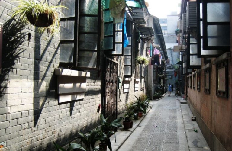 A narrow alley with green plants and windows.