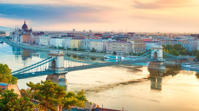 Panoramic view of Budapest at sunset showing the Chain Bridge over the Danube with the Parliament on the left.